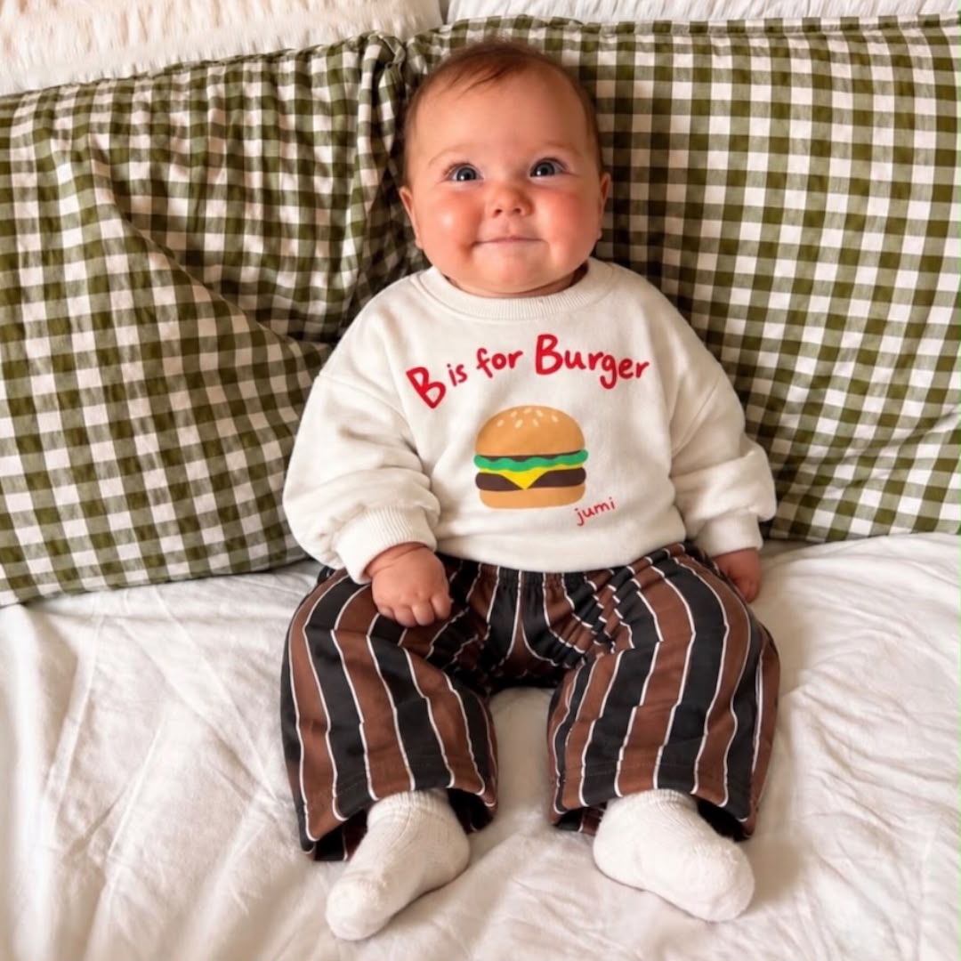 Baby wearing cream burger graphic sweatshirt and brown striped trousers