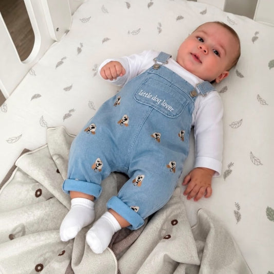 Baby wearing Little Dog Lover Denim Dungaree Set lying in crib