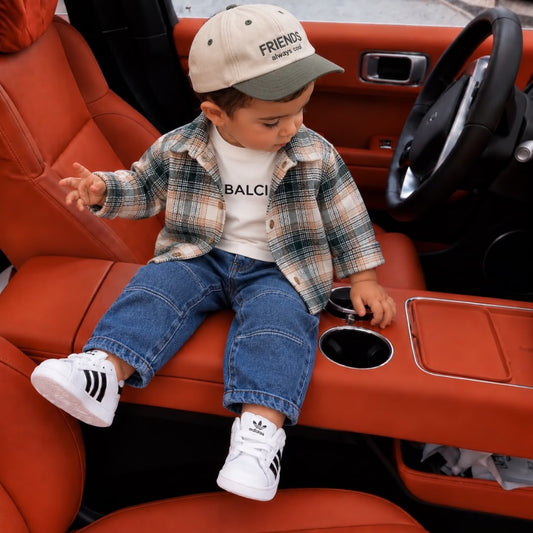 Toddler wearing green plaid overshirt, white printed T-shirt, blue jeans and cap