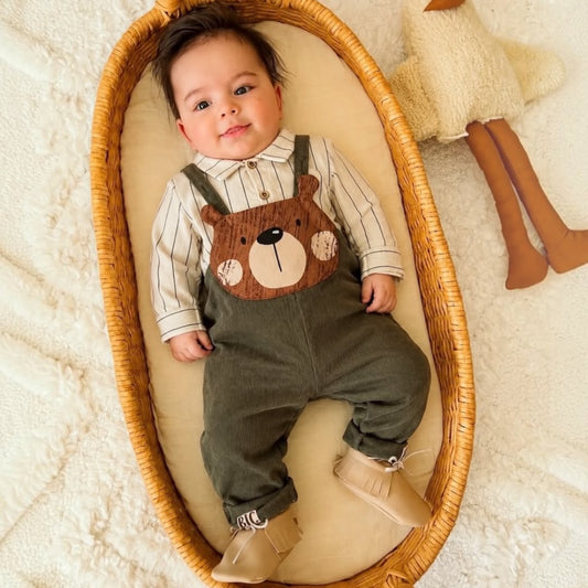 Baby wearing olive green Bear Face Dungaree Set in basket