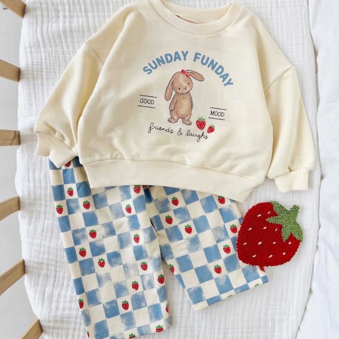 Sunday Funday bunny baby sweatshirt and blue strawberry checkered trousers laid flat