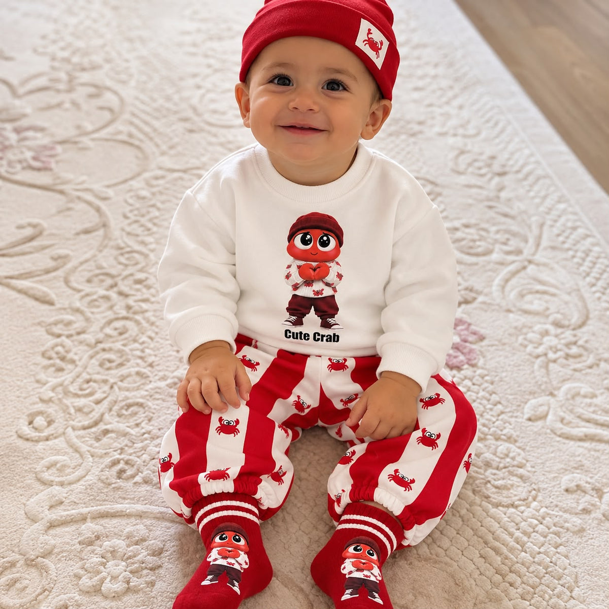 Baby wearing red crab sweatshirt striped joggers red beanie and socks