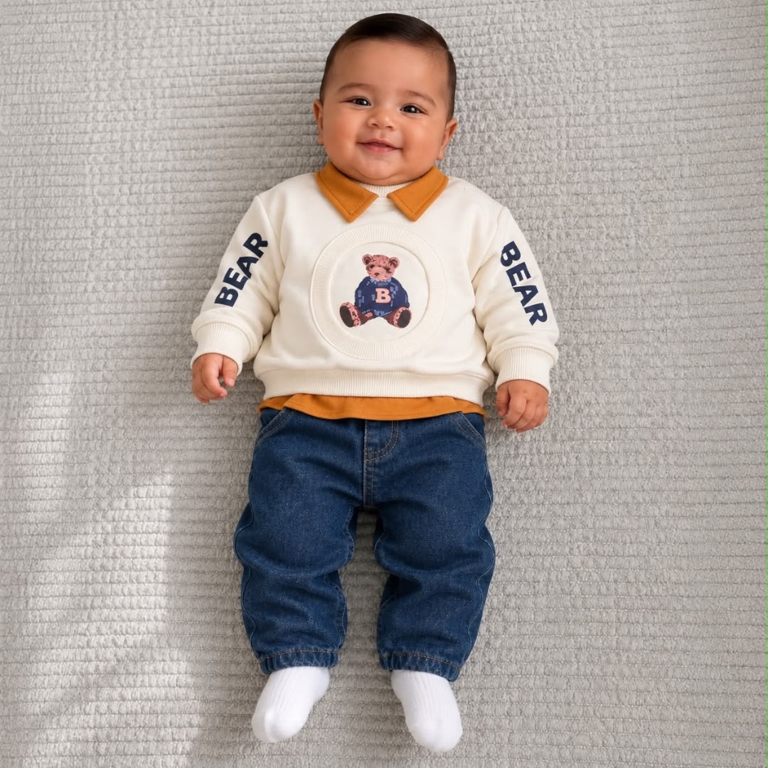 Baby wearing cream teddy bear sweatshirt with mustard collar and blue jeans
