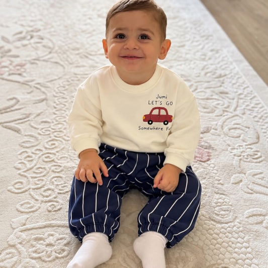 Baby wearing cream red car sweatshirt and navy striped joggers