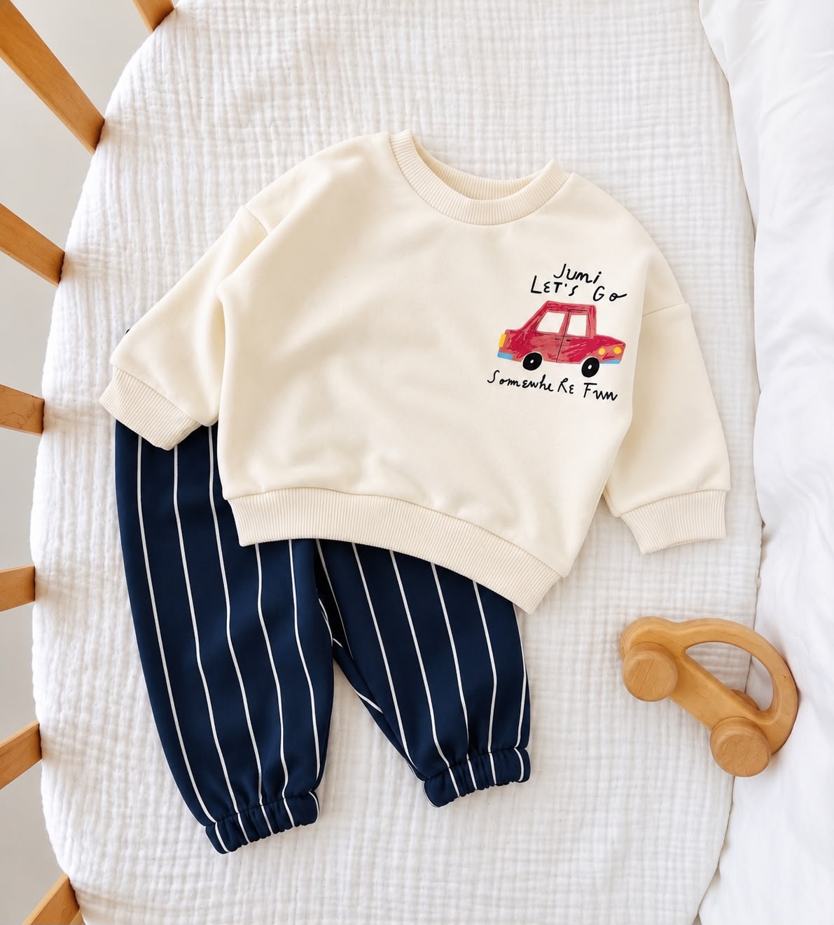 Cream red car baby sweatshirt with navy and white striped joggers laid flat