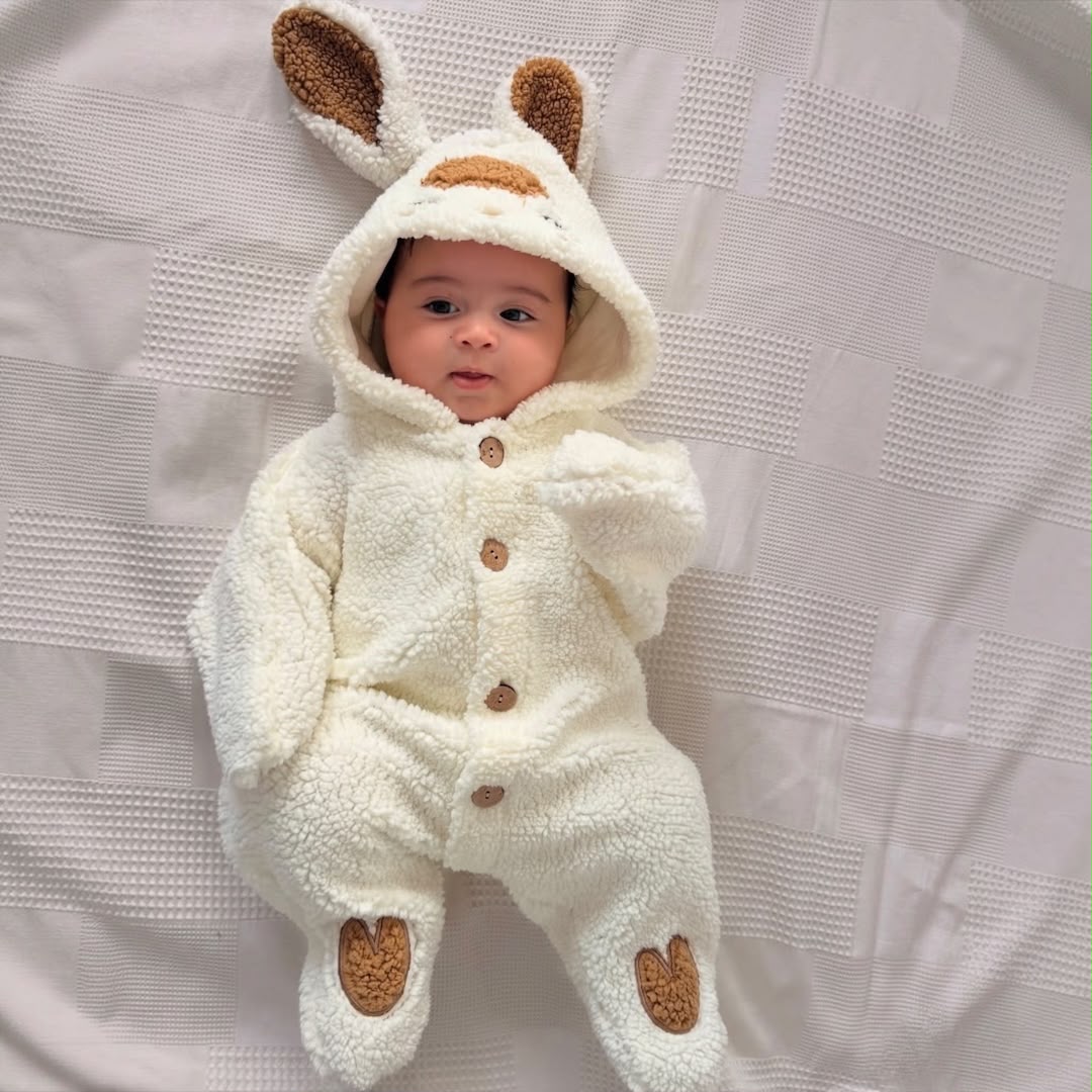 Baby wearing cream fluffy hooded pramsuit with long ears and brown details
