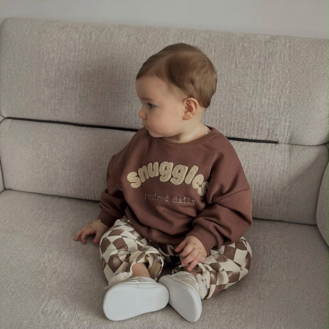 Baby wearing a brown sweatshirt and checkered pants set