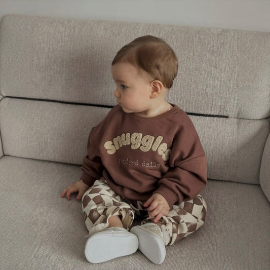 Baby wearing a brown sweatshirt and checkered pants set