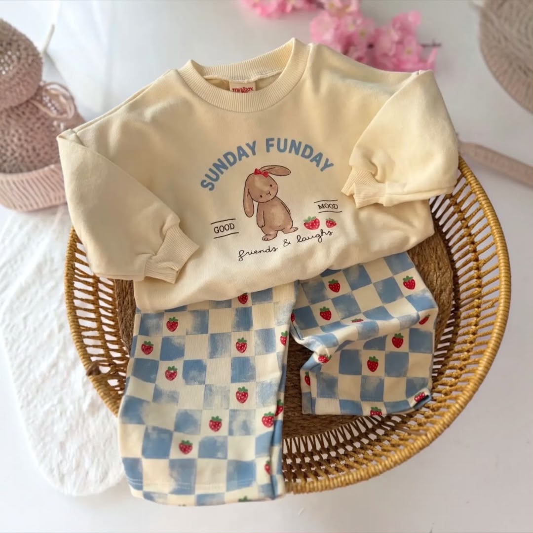 Cream Sunday Funday bunny sweatshirt with blue checkered strawberry trousers in a basket