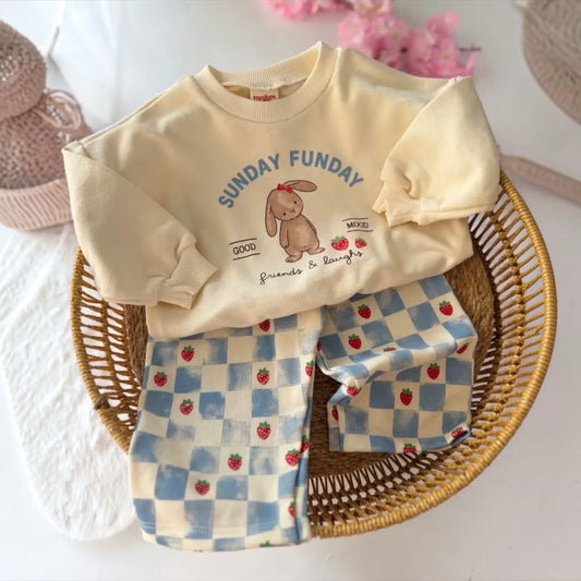 Cream Sunday Funday bunny sweatshirt with blue checkered strawberry trousers in a basket