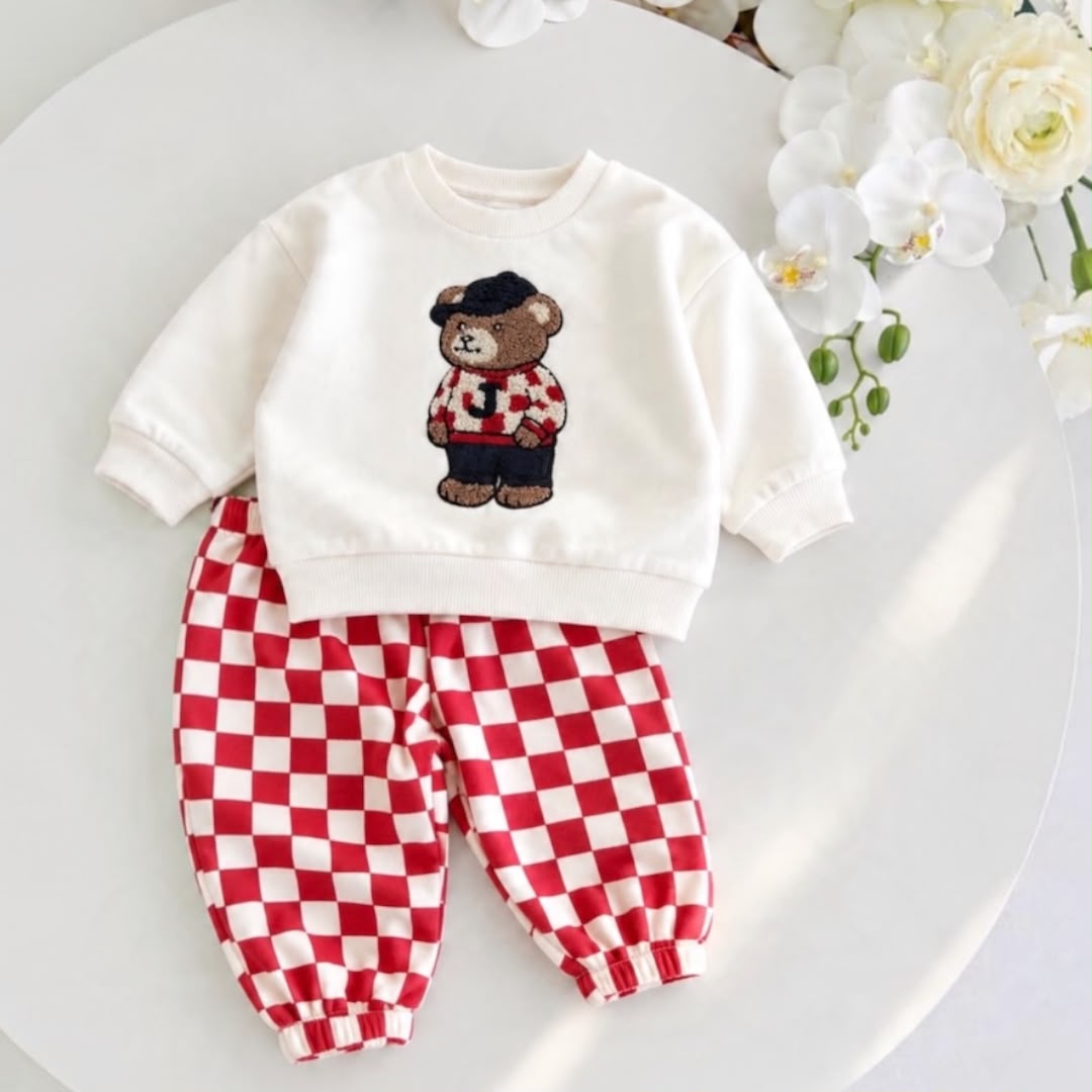 Cream teddy bear baby sweatshirt with red and cream checkered joggers laid flat