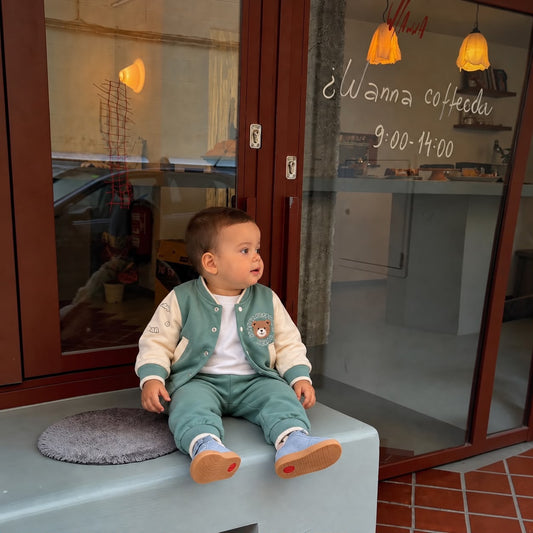 Toddler wearing sage green bear varsity jacket and matching green joggers